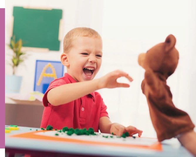 A young boy playing with a teddy bear.